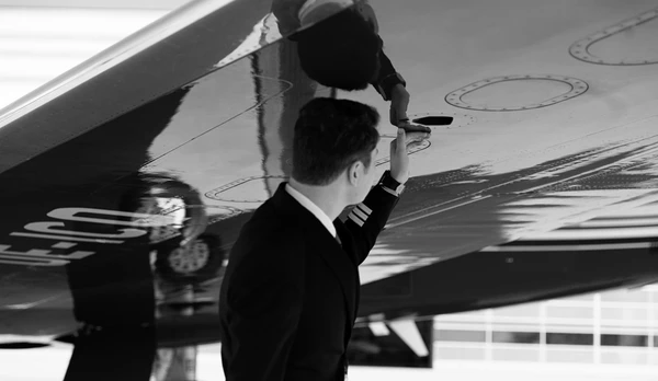 A pilot inspecting the underside of a wing to ready the business jet for takeoff.